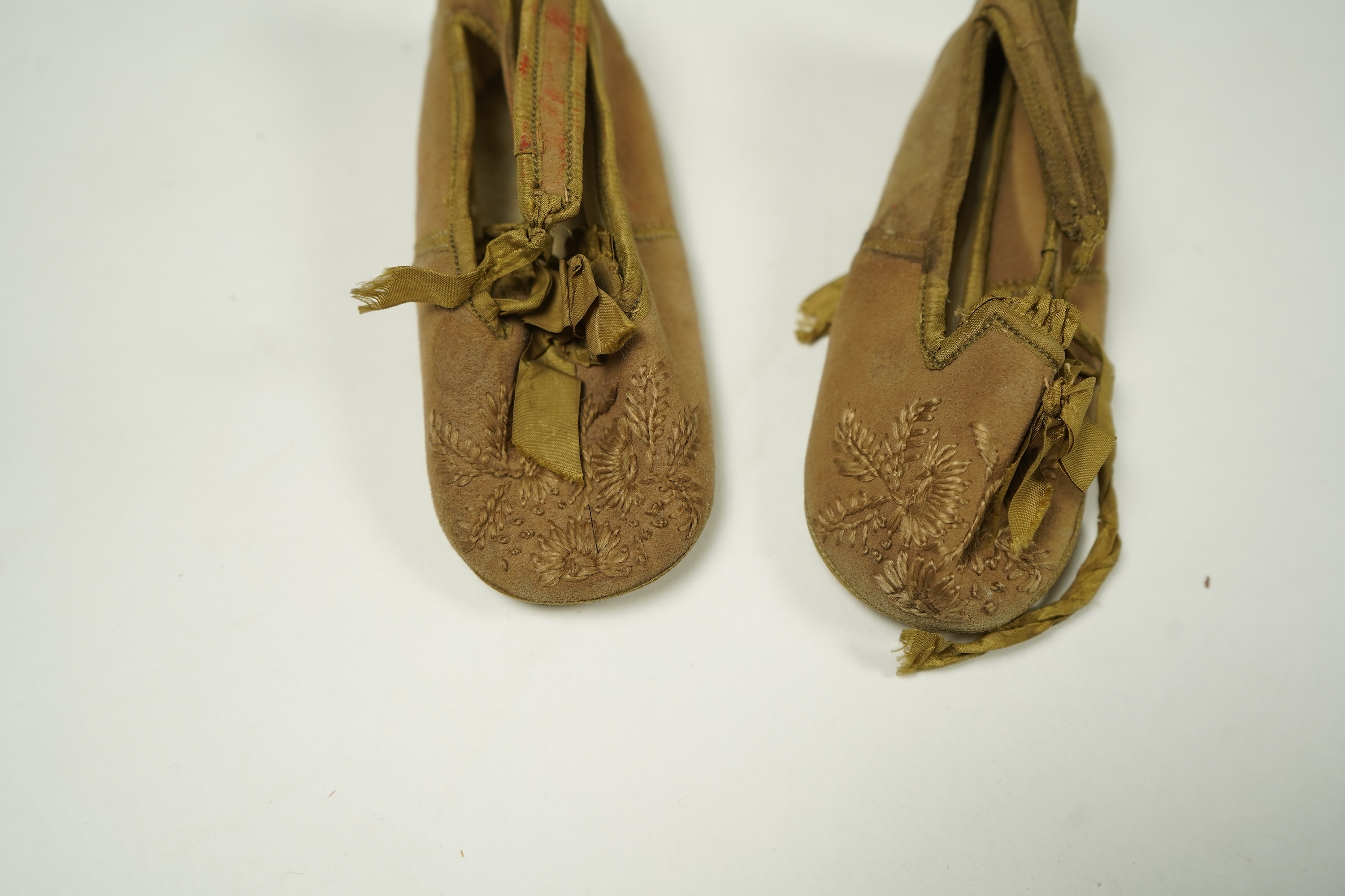 An unusual pair of Edwardian ladies red velvet and gold embroidered mules, a pair of 19th century ladies cream silk shoes and a pair of baby's embroidered suede shoes. Mules stamped 41at toe of sole. Condition - all thre